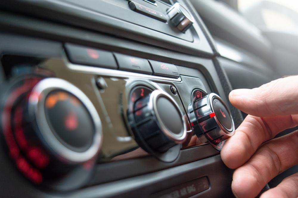 Townsville mechanic adjusting the air conditioning temperature dial on a car's control panel