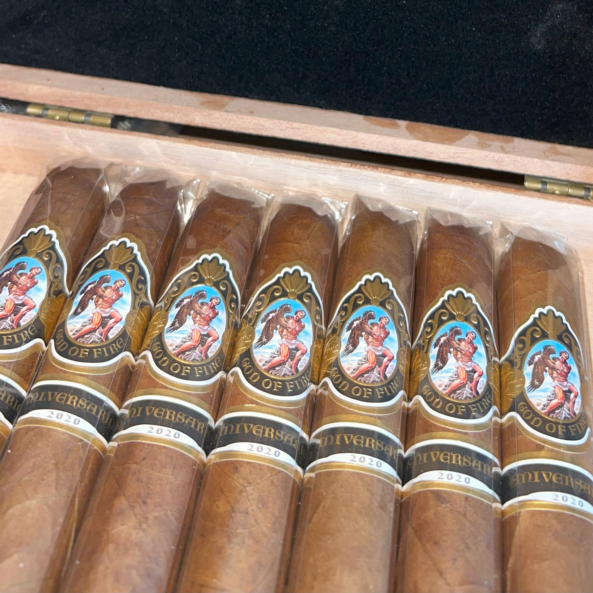 Open wooden box holding neatly arranged cigars with colorful oval labels