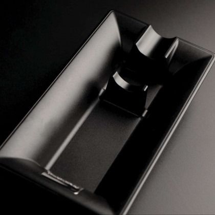 Black glossy metal tray with a central raised divider on a dark background