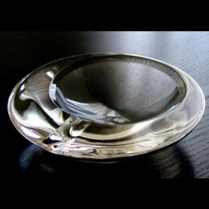 Clear glass ashtray on a dark tabletop, lit from above