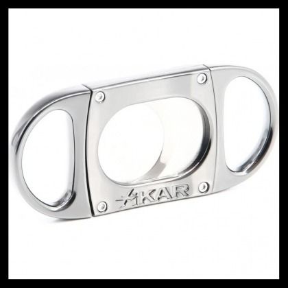 Silver metal cigar cutter with oval cutouts and the engraved word “AKAR” on a white background