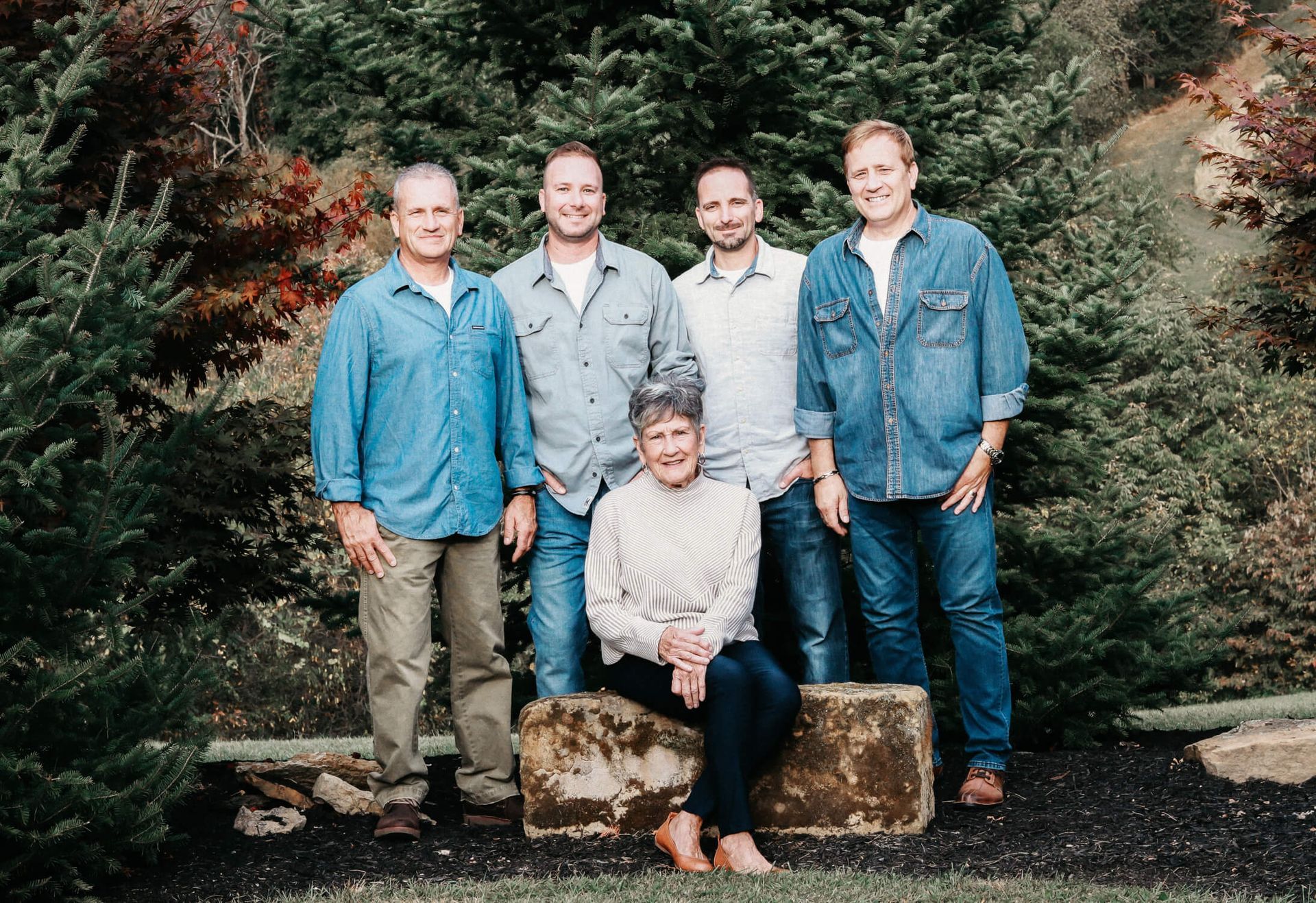 A group of people are posing for a picture in front of trees.