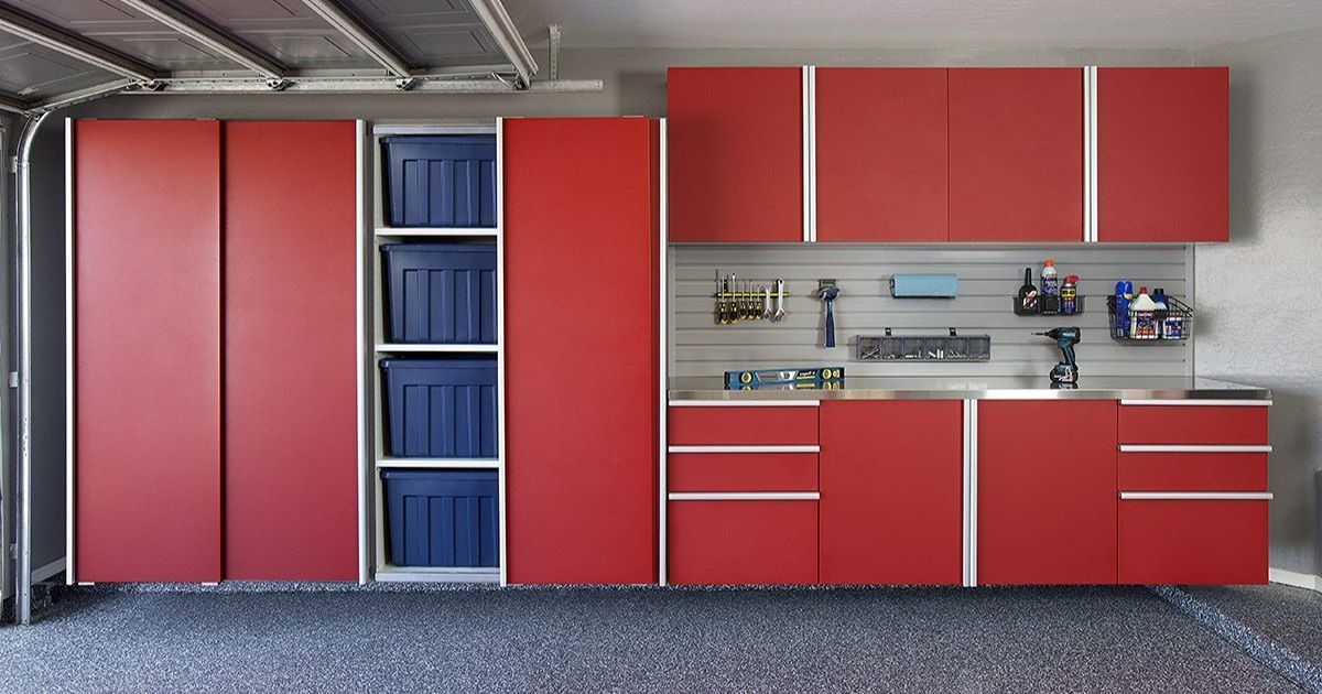 Red garage cabinets and shelving with tools, blue storage bins, and a concrete floor.