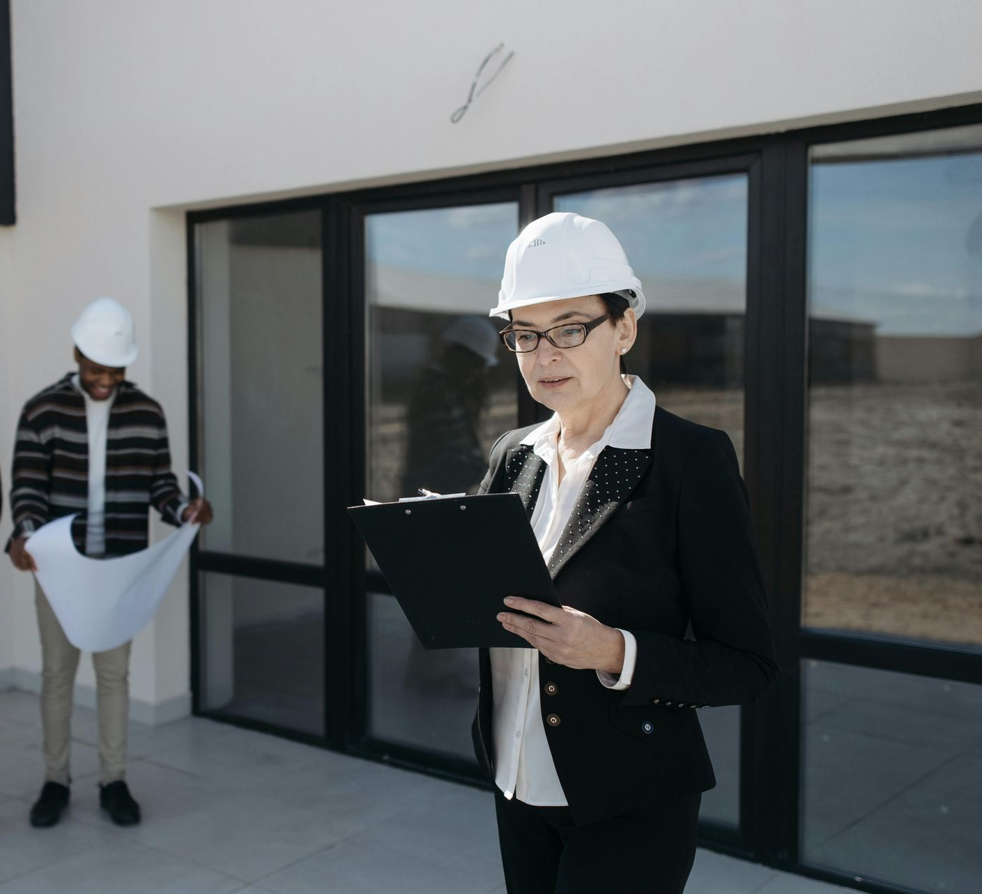 Two people in hard hats reviewing plans outside a modern building in Parkersburg Ohio