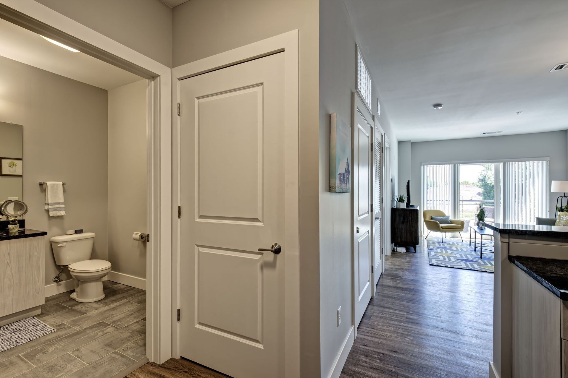 A hallway in a house with a toilet and a bathroom.