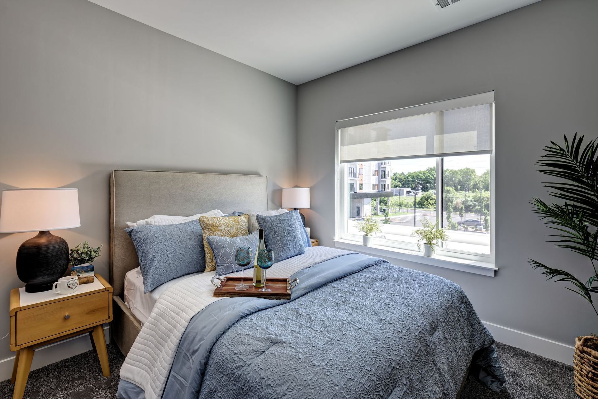 A bedroom with a bed , nightstand , lamps and a window.