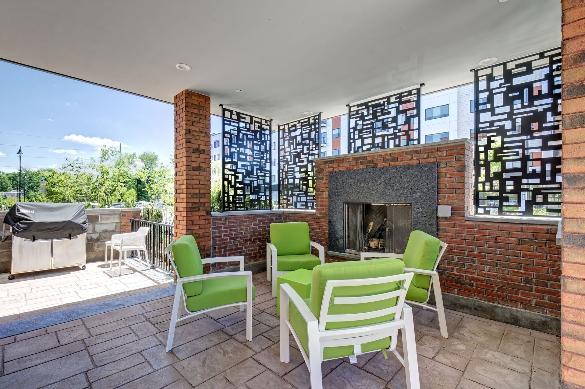 A patio with green chairs and a fireplace.
