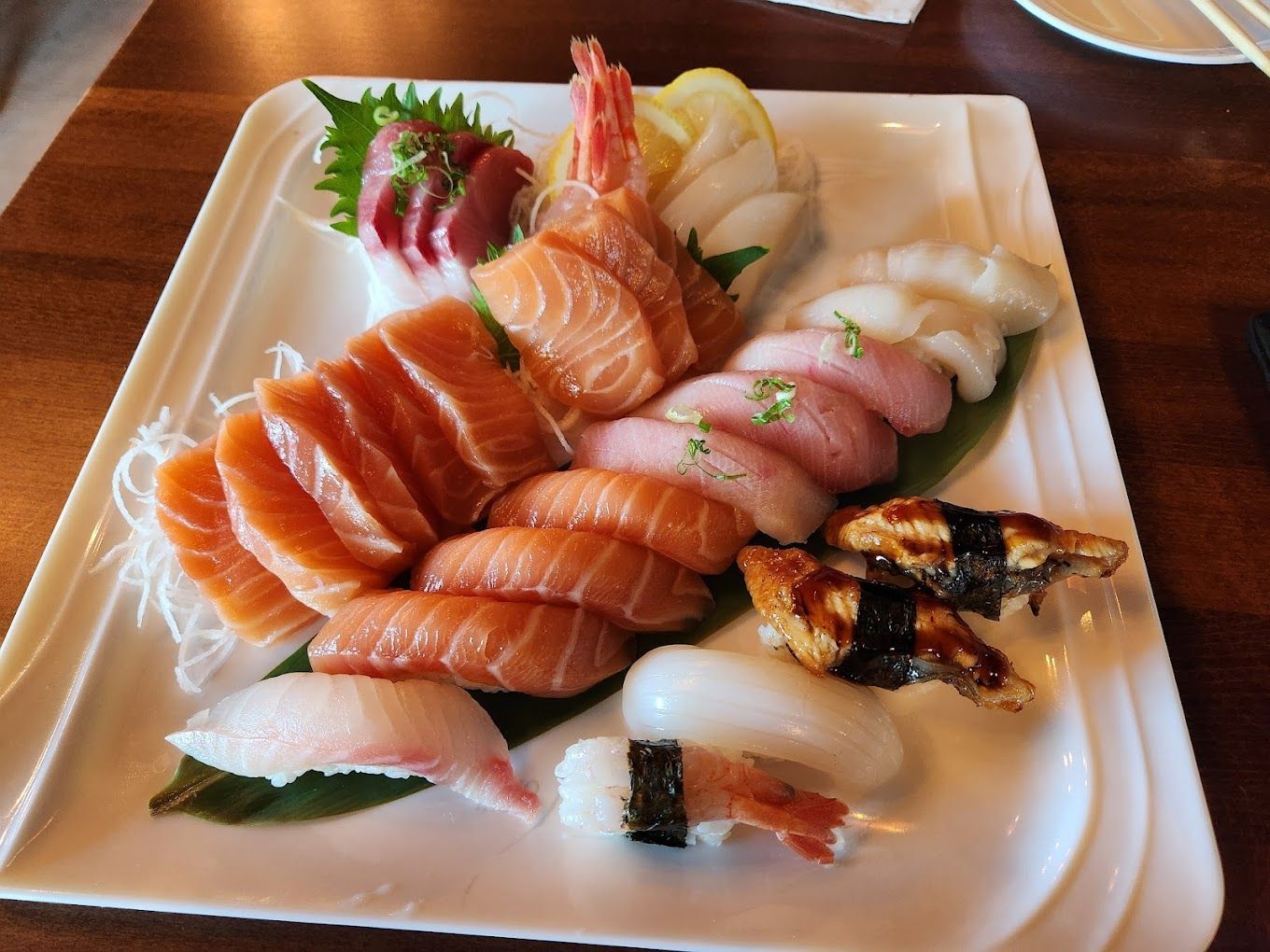 Sushi platter with assorted nigiri and sashimi on stacked white plates