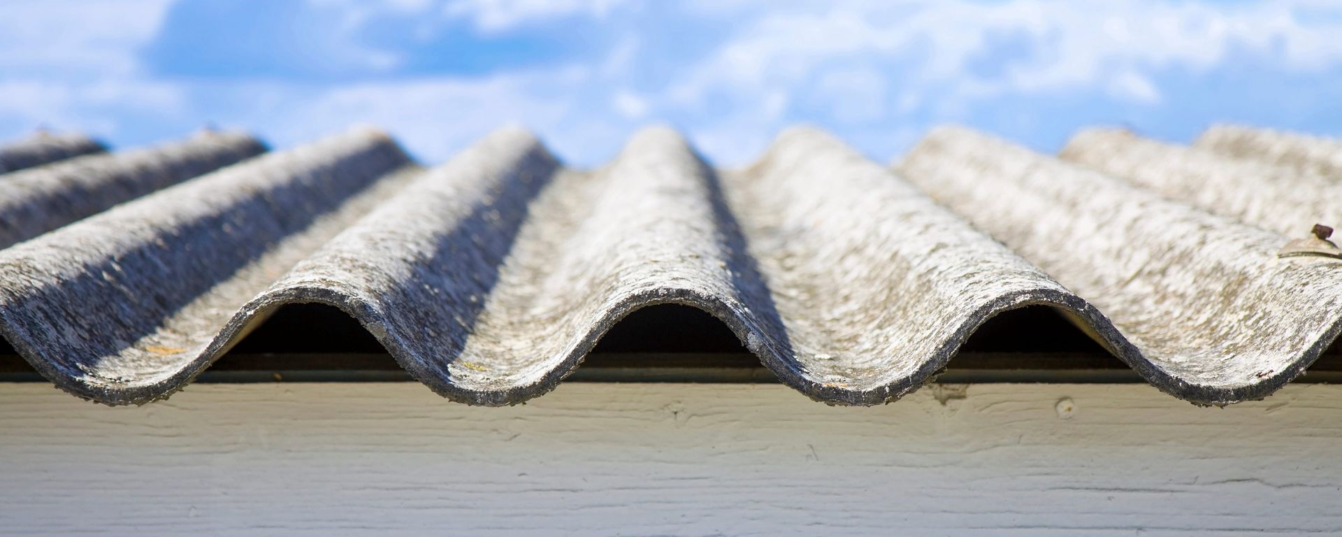 Close-up of a gray corrugated roof panel against a pale sky