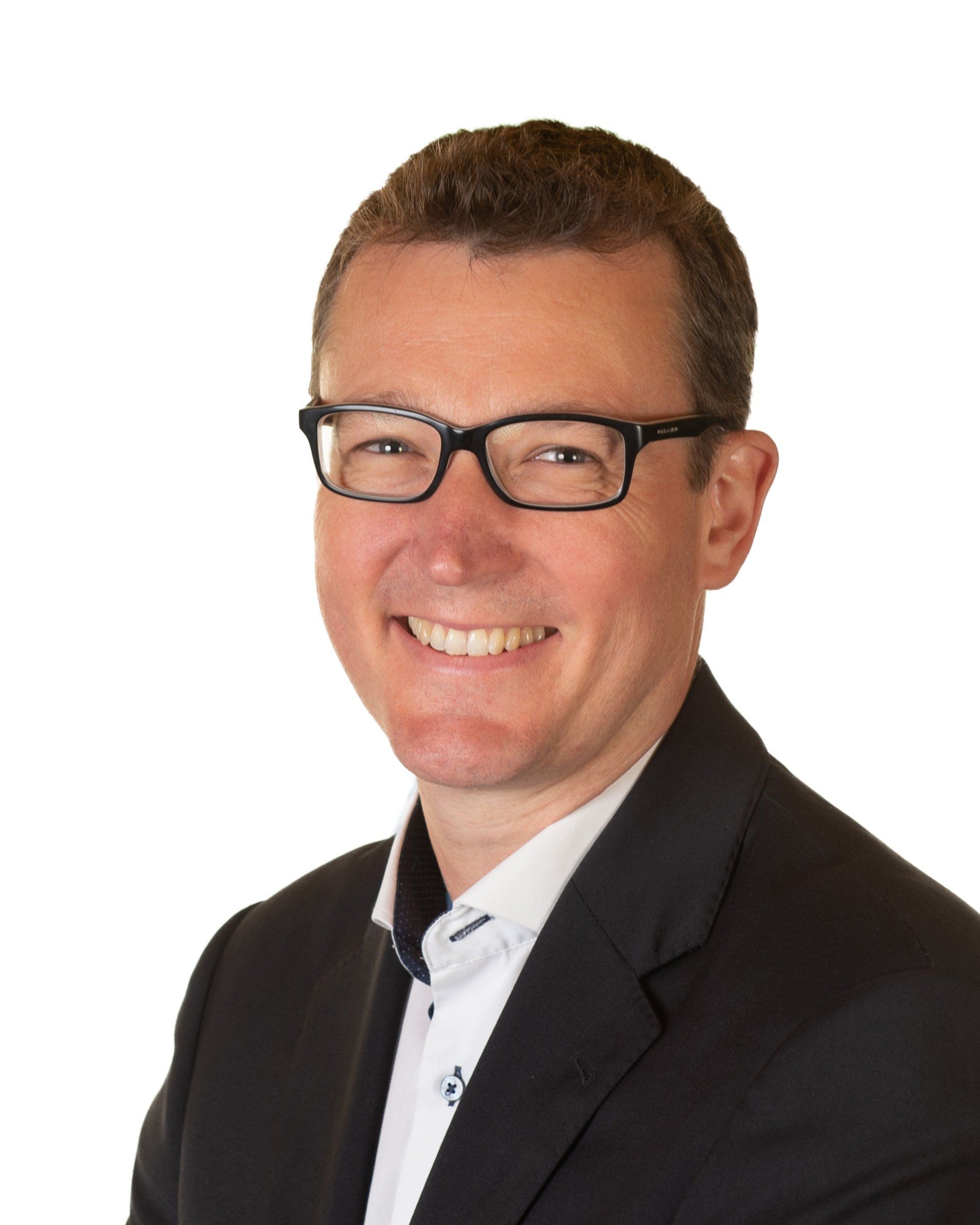 Headshot of a smiling person wearing glasses, a white collared shirt, and a dark blazer against a white background.