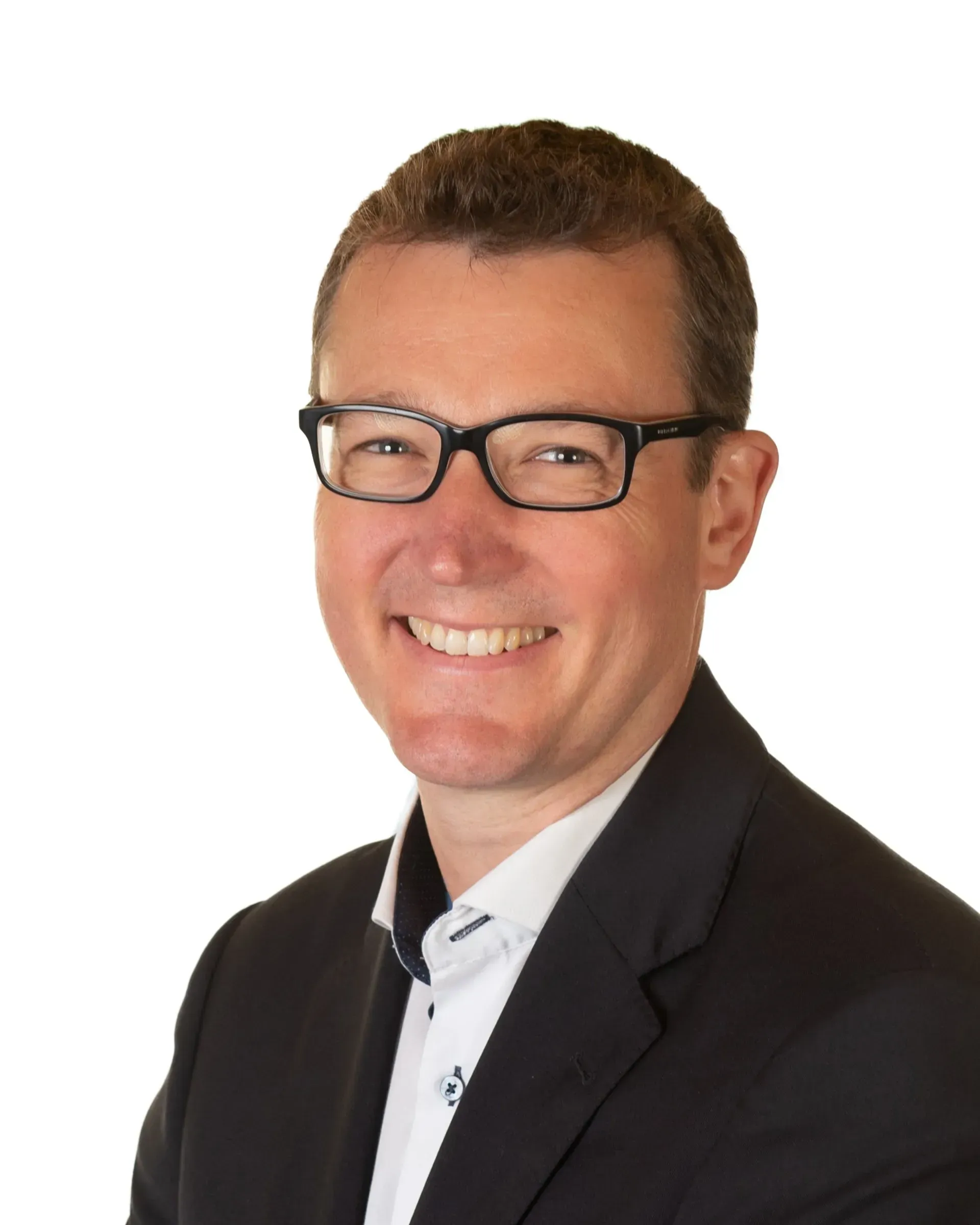 Headshot of a person smiling, wearing glasses, a white collared shirt, and a dark blazer against a white background.