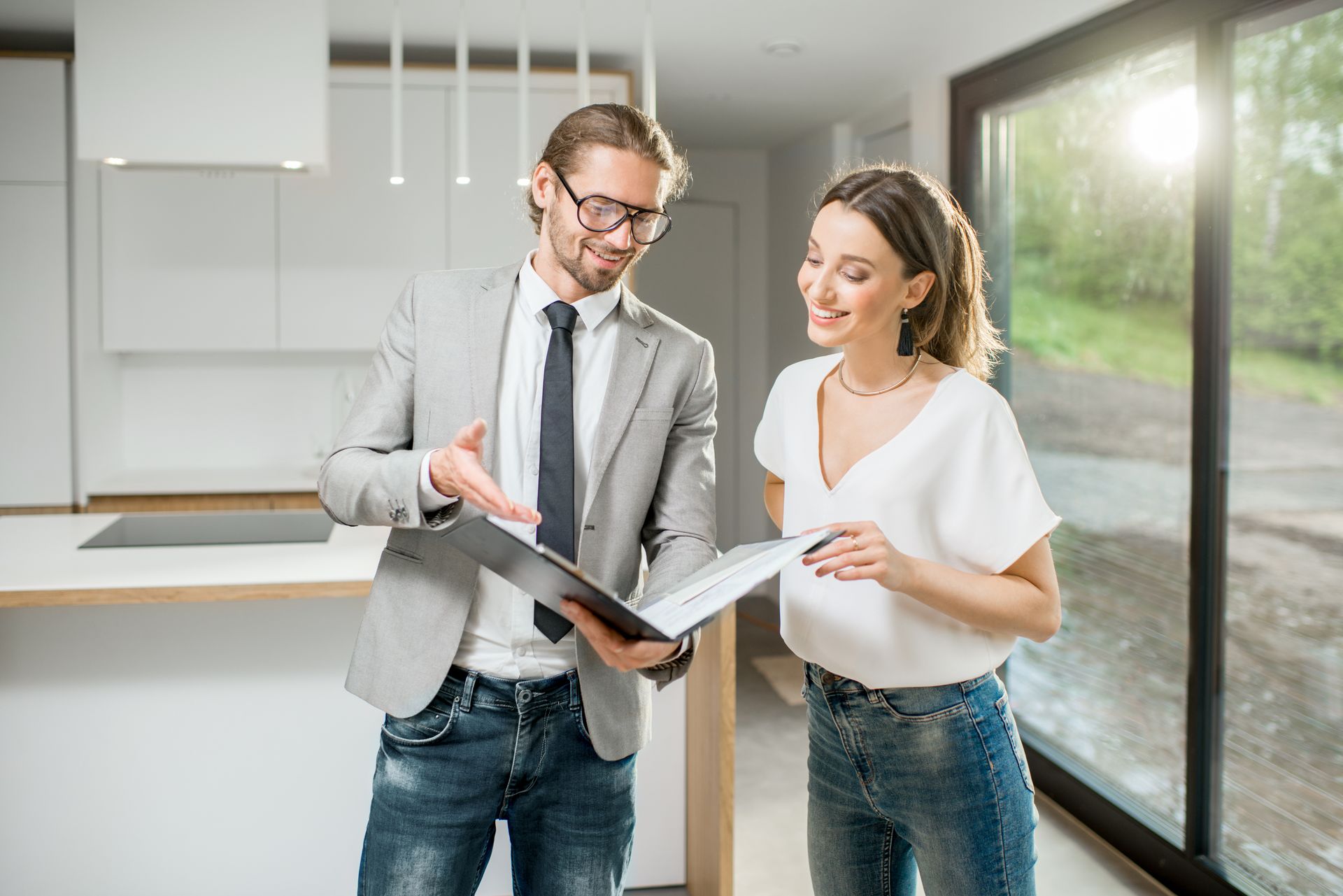 Real estate agent showing paperwork to a client in a modern kitchen with natural light