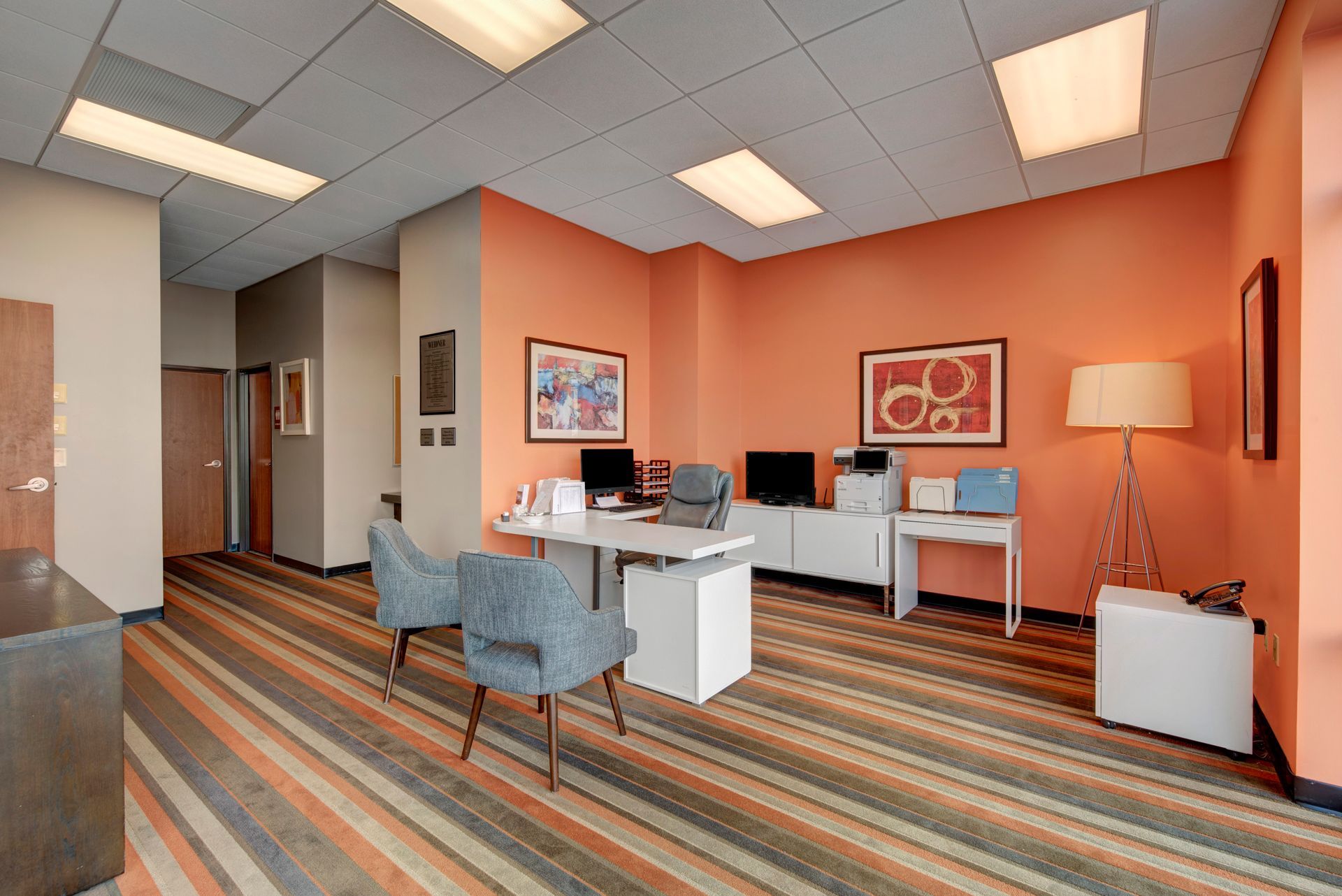 A large room with orange walls and a striped carpet.