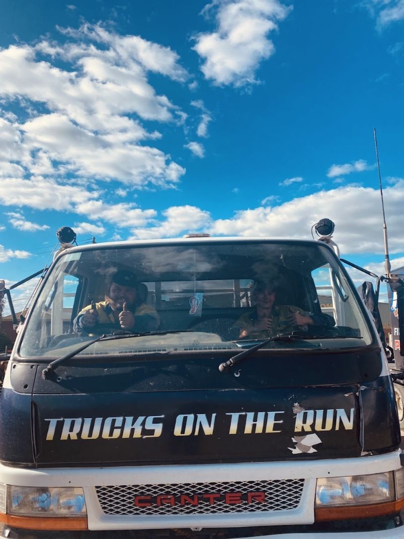 A Man is Driving a Truck With the Words — Trucks On The Run Pty Ltd in Gatton, QLD