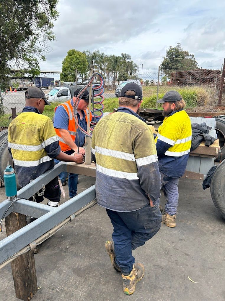 A Group of Men Are Working on a Trailer in a Parking Lot — Trucks On The Run Pty Ltd in Charlton, QLD