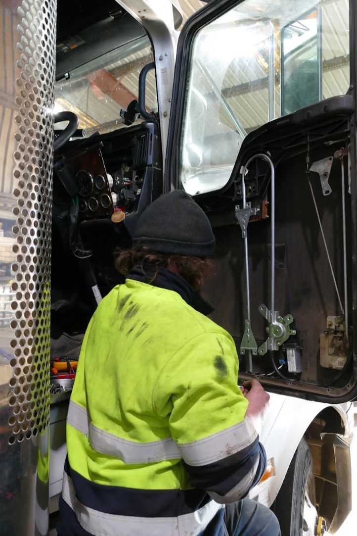 A Man in a Yellow Jacket is Working on a Truck — Trucks On The Run Pty Ltd in Glenvale, QLD
