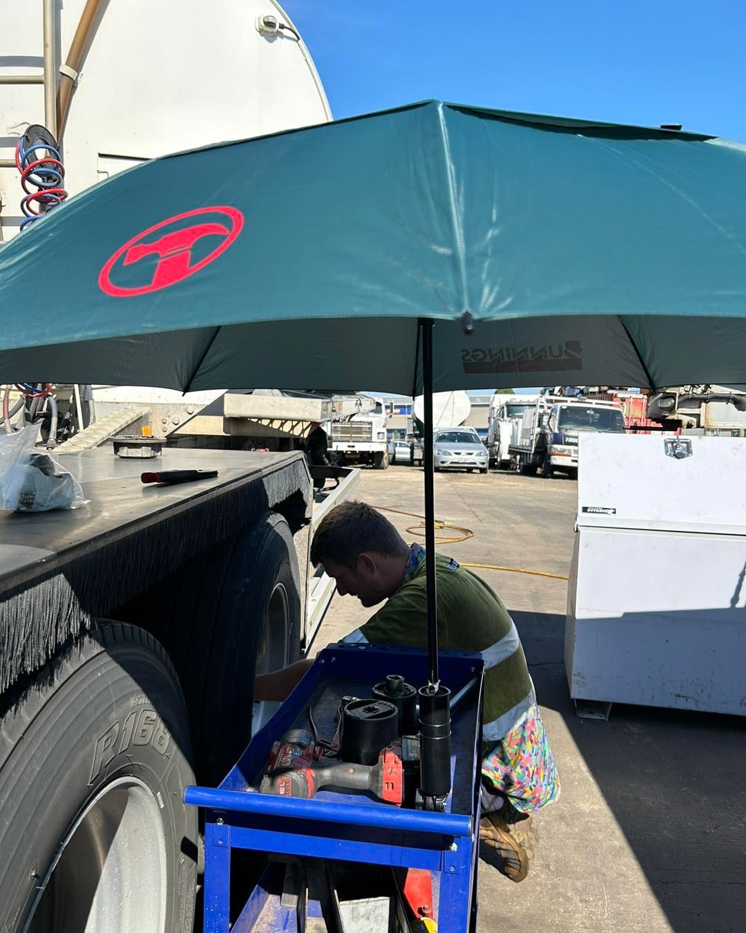 A Man is Working on a Truck Under an Umbrella — Trucks On The Run Pty Ltd in Cambooya, QLD