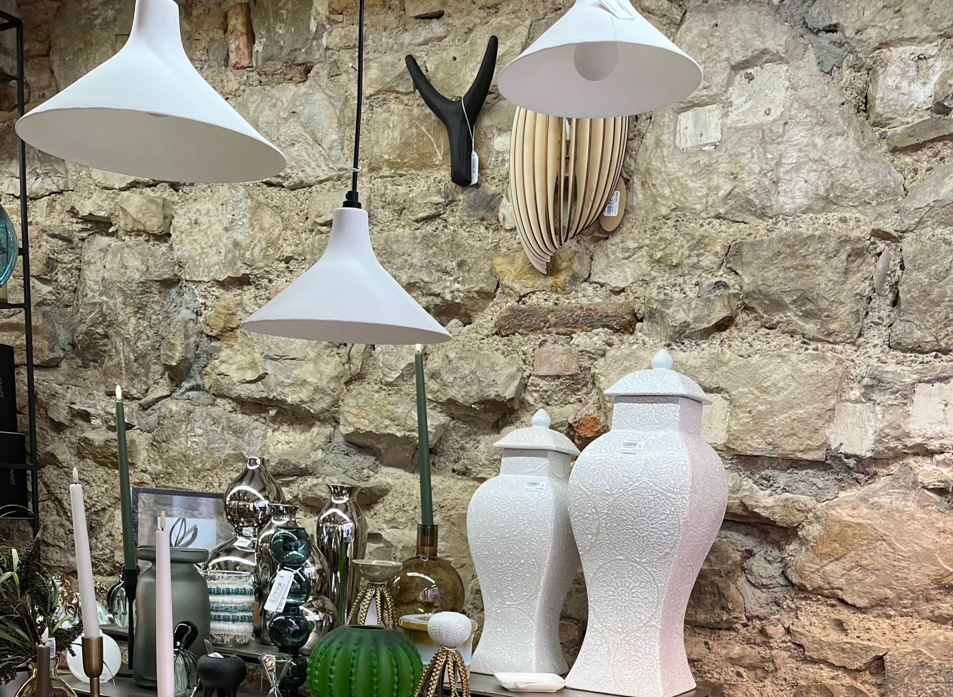 Un groupe de vases blancs est posé sur une table devant un mur de pierre.