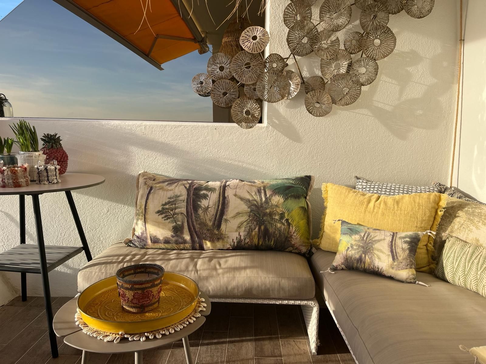 Un patio avec un canapé, une table et un tableau sur le mur.