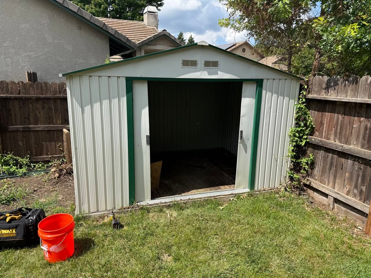 Shed Removal and Demolition Services in Butte County, CA — before: open white-and-green shed in fenced backyard
