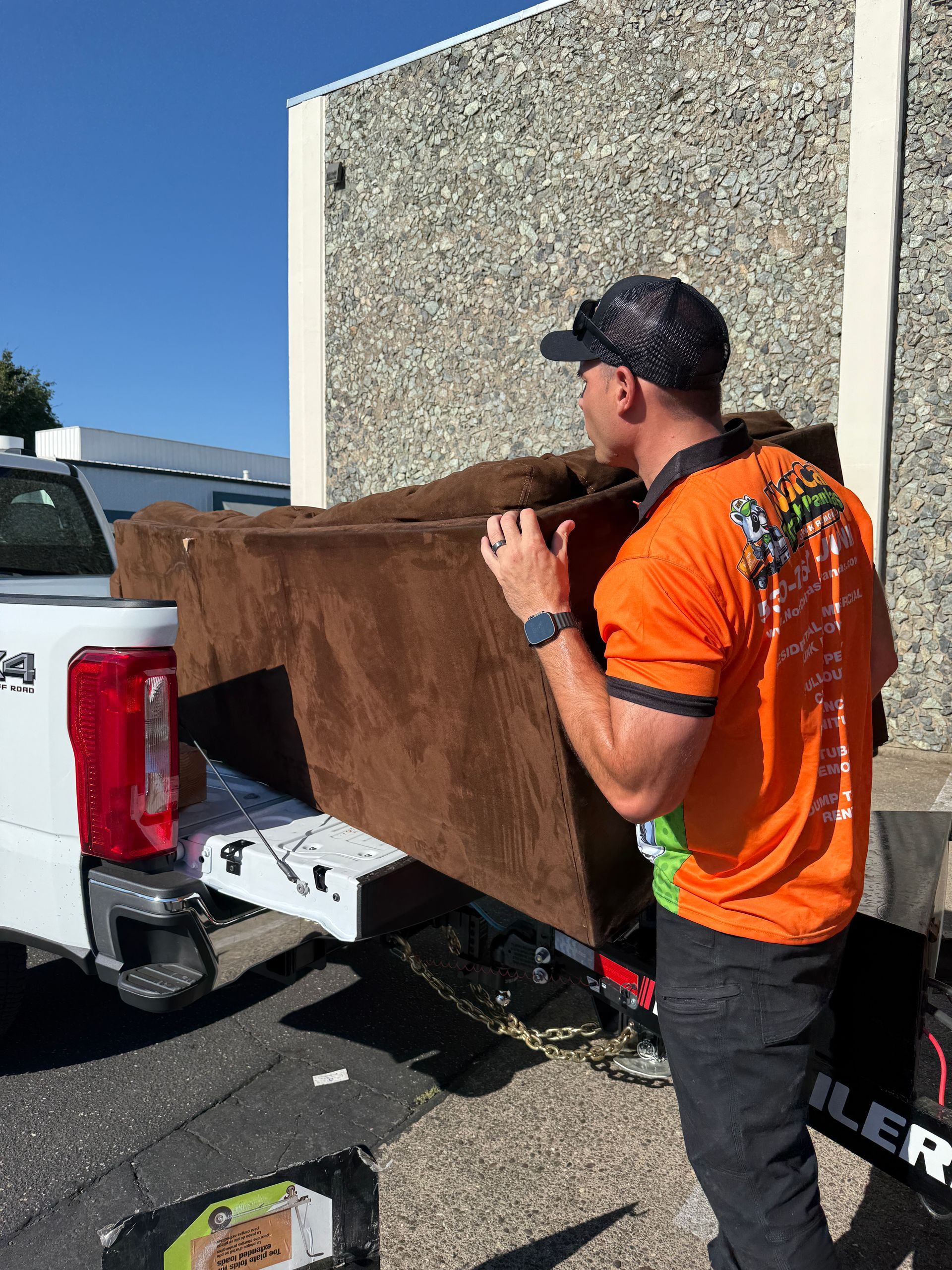 Two men are carrying a wooden cabinet in a living room.