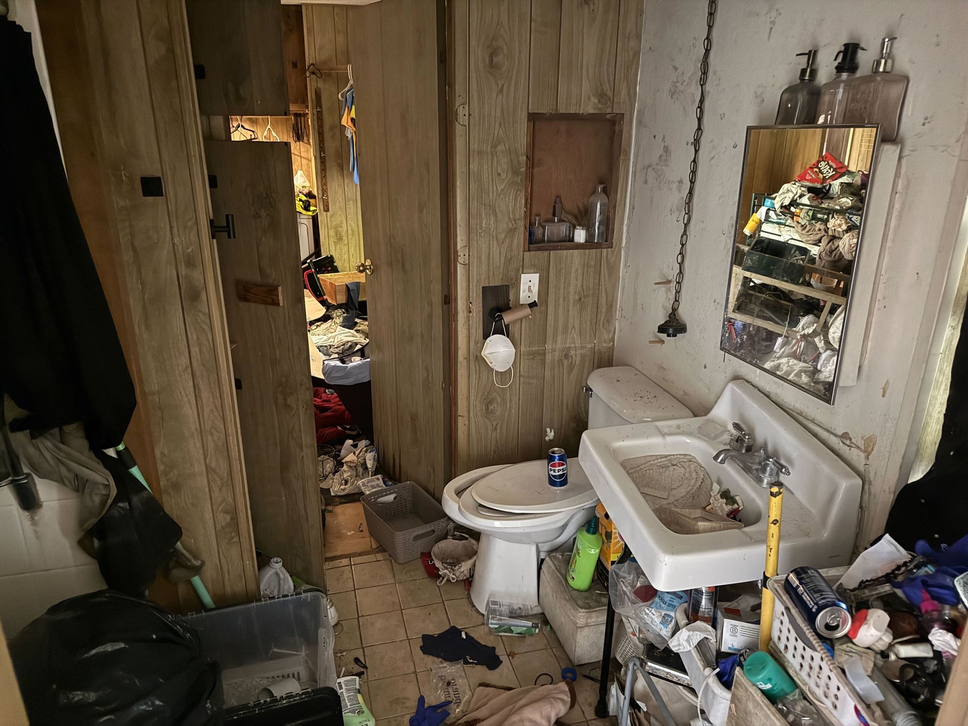 Hoarder cleanout in Gridley, CA — before: dirty bathroom with stained sink and clutter