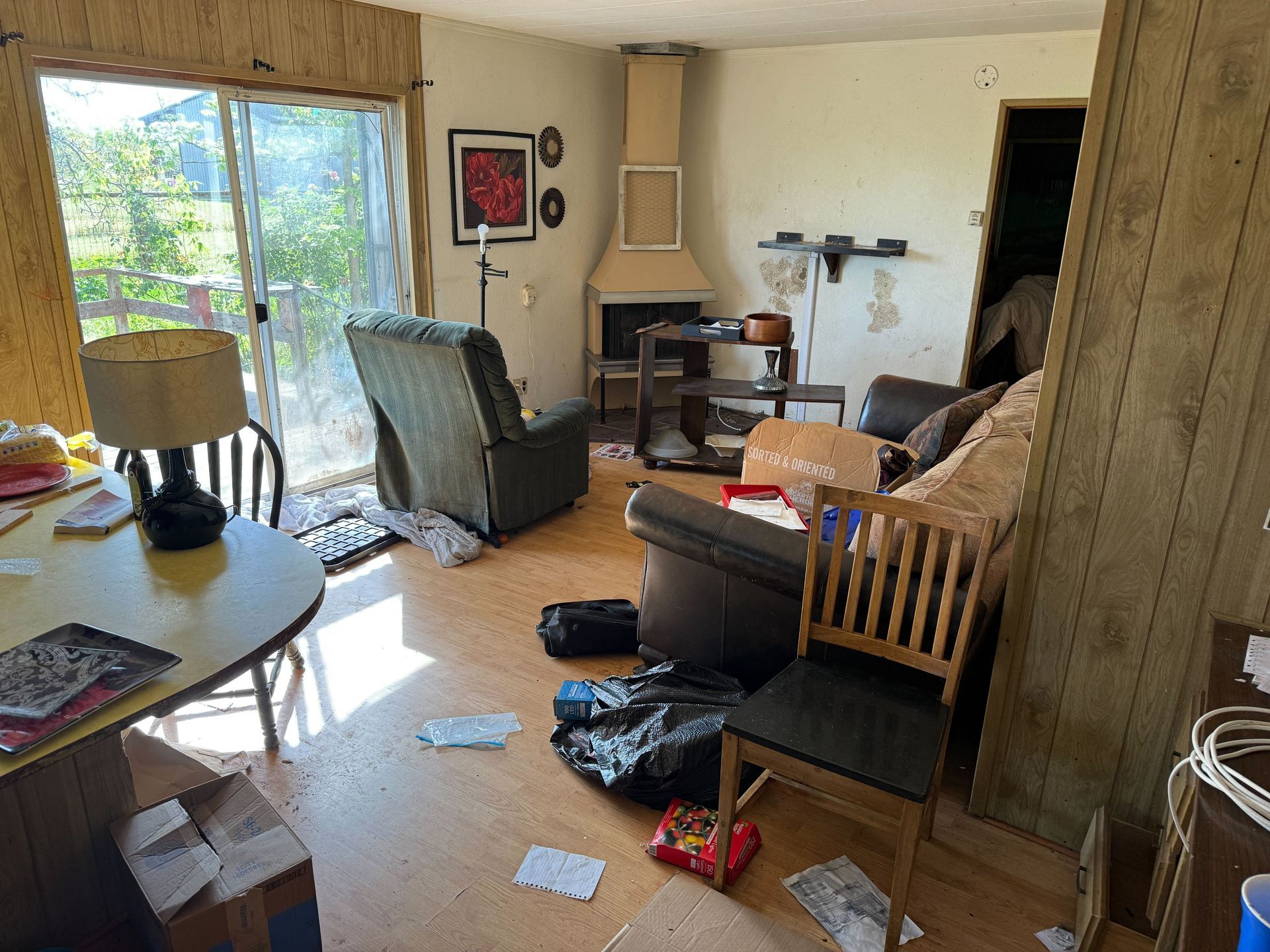Hoarder cleanout in Gridley, CA — before: living room packed with furniture, boxes and clutter
