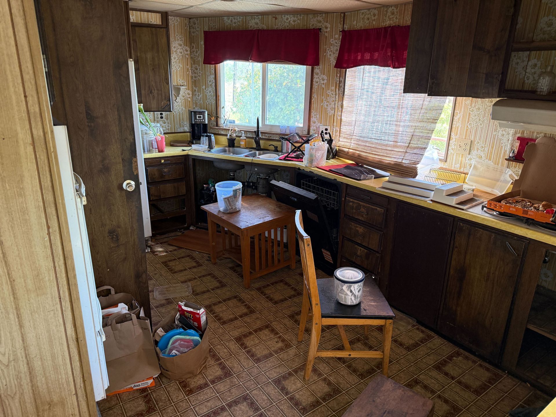 Hoarder cleanout in Gridley, CA — before: kitchen with red curtains and cluttered counters