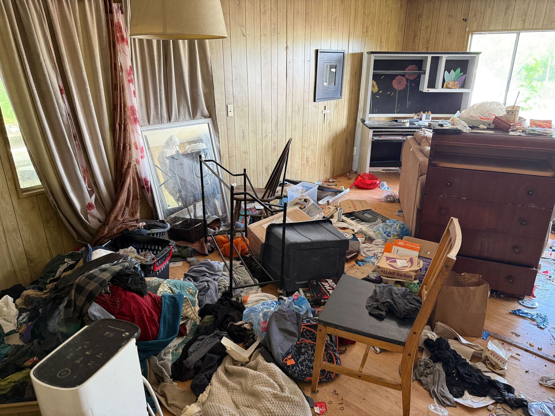 Hoarder cleanout in Gridley, CA — before: bedroom with clothes, boxes and clutter everywhere
