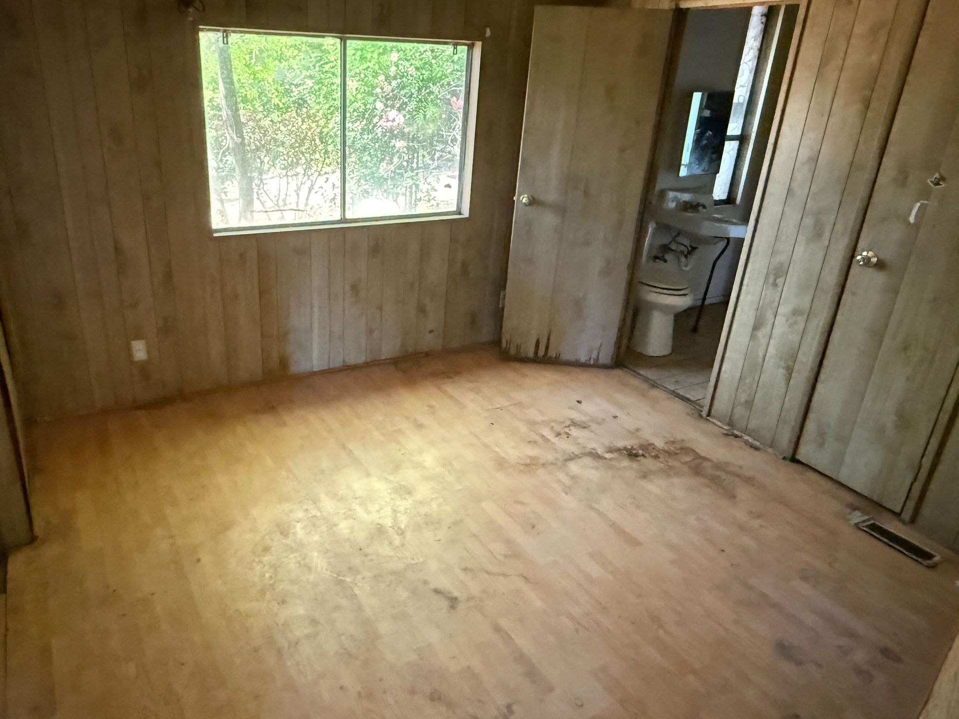 Hoarder cleanout in Gridley, CA — after: empty room with window and doorway to bathroom