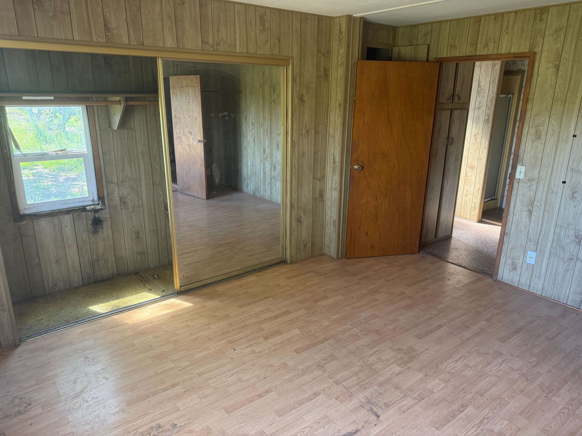 Hoarder cleanout in Gridley, CA — after: empty wood-paneled room with mirrored closet doors
