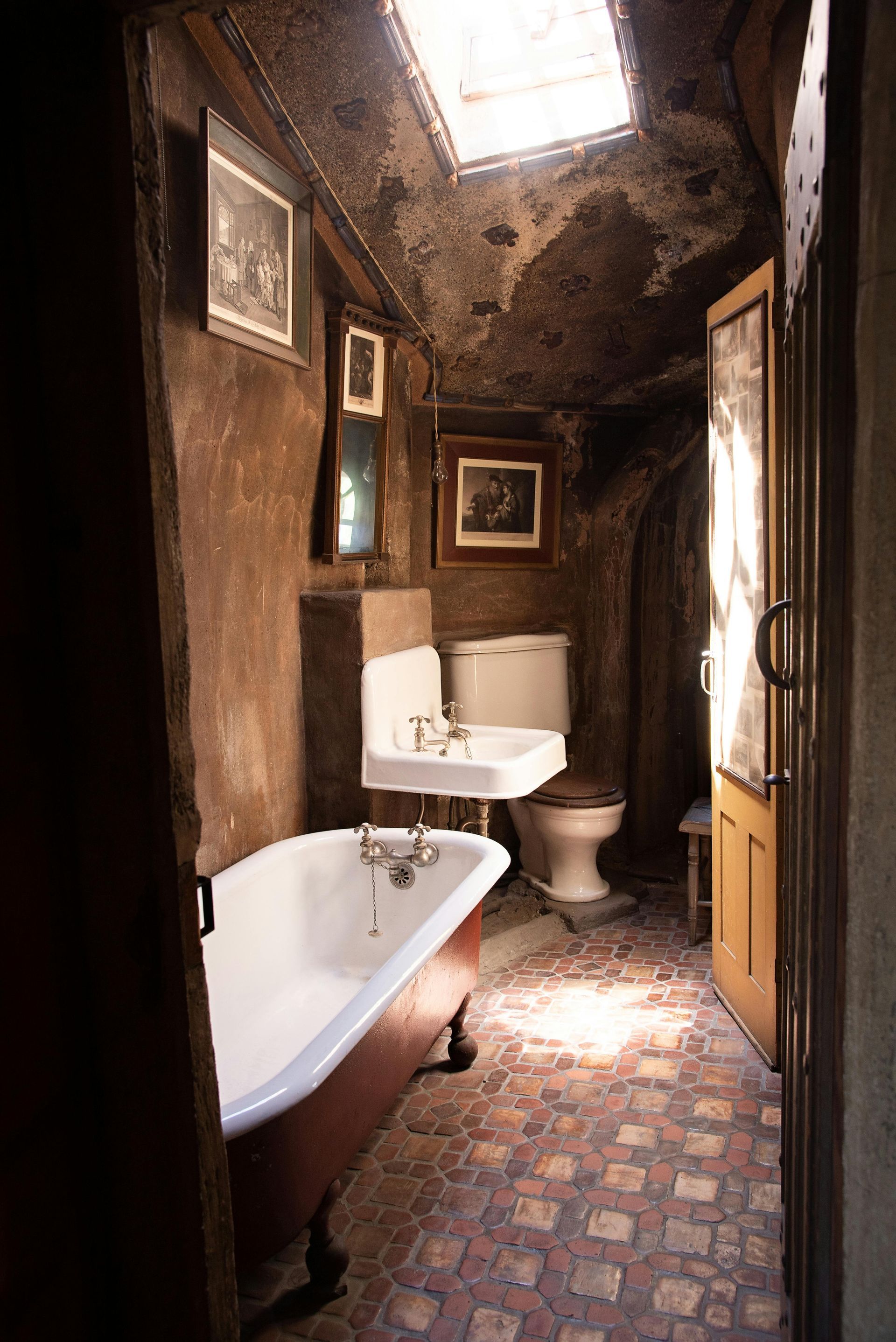 A bathroom with a tub , sink , toilet and skylight.