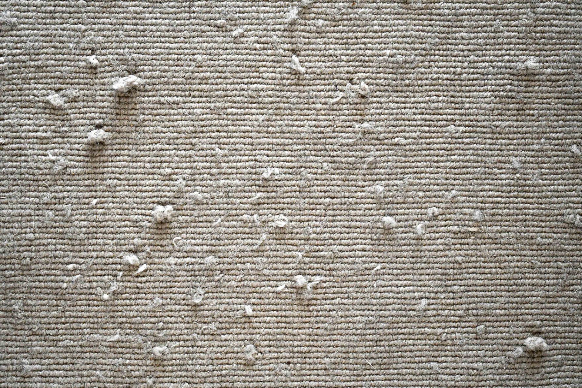 Close-up of a beige textured fabric with scattered white specks and raised spots Close-up of a beige textured fabric with scattered white specks and raised spots