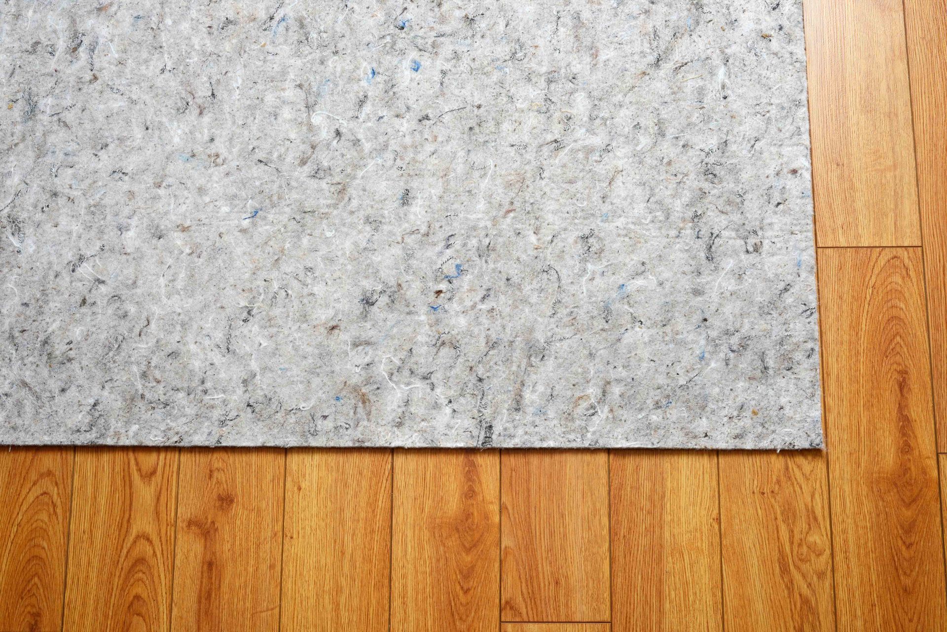 Gray rug on a hardwood floor with a wood trim edge visible on the right Gray rug on a hardwood floor with a wood trim edge visible on the right