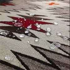 People cleaning a carpet with a white handheld vacuum and yellow gloves
