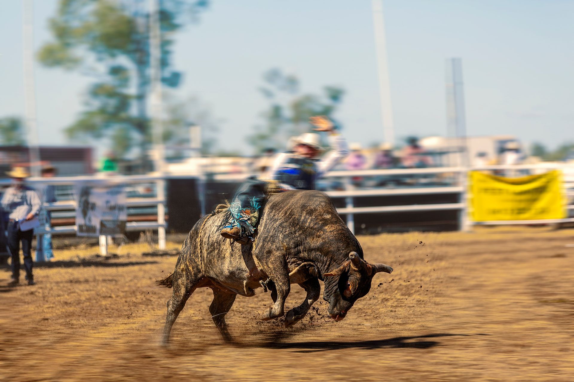 Bull rider on a bucking bull at a rodeo in a dirt arena, action shot with blurred background.