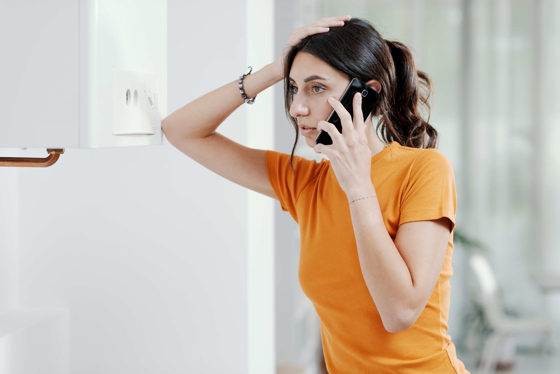 a woman in an orange shirt is talking on a cell phone