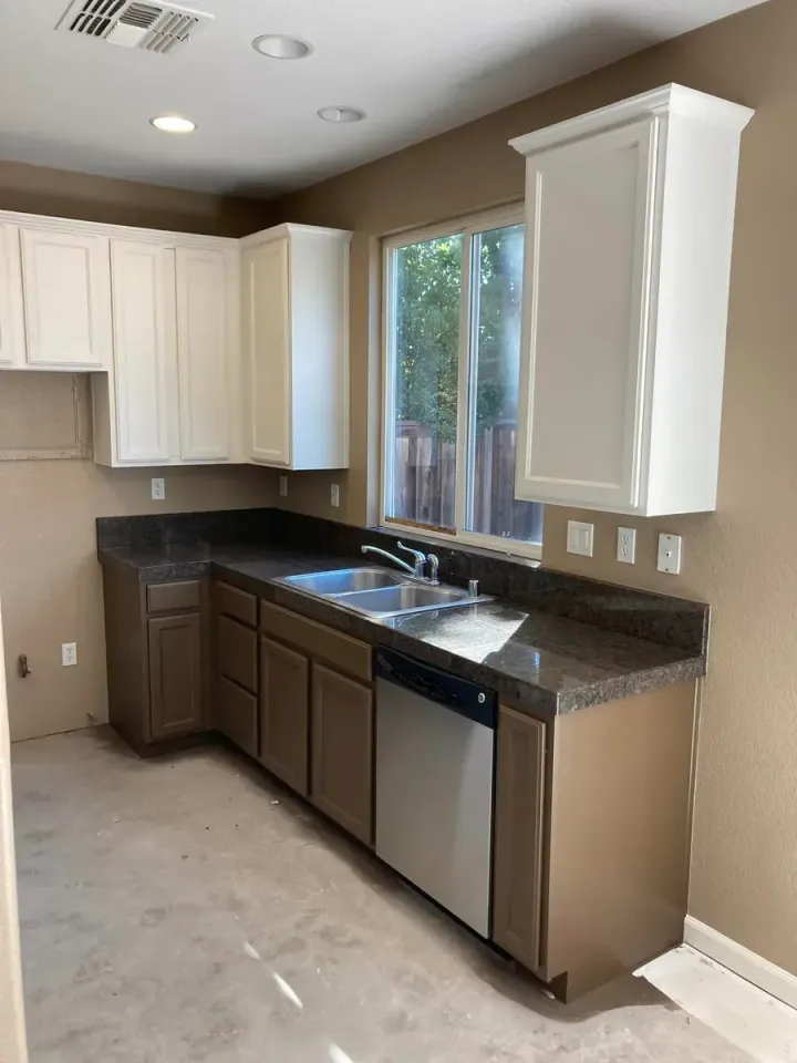 Kitchen with brown and white cabinets, granite countertops, and a stainless steel dishwasher.