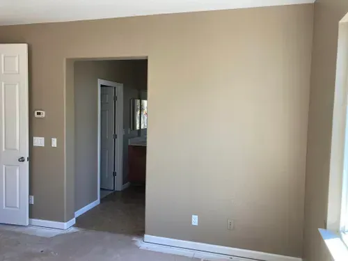 A beige-painted room with an open doorway to a bathroom, white door, and window.