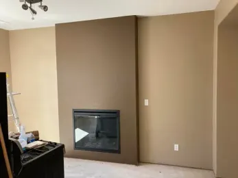 Fireplace in a brown wall with lighter brown surrounding walls.