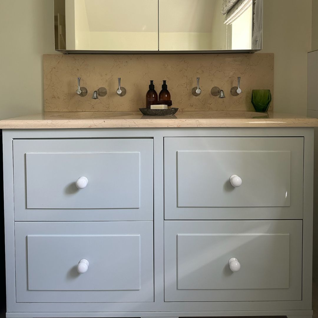 Bathroom vanity with blue drawers, stone countertop, silver faucets, and a mirrored cabinet.