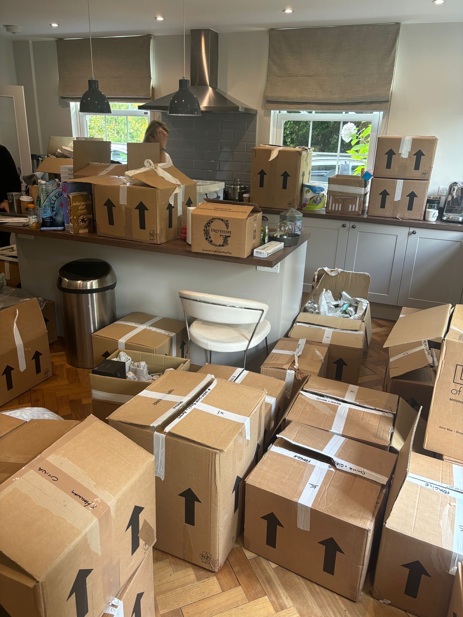 Boxes stacked in a kitchen, some on counters and some on the floor. Arrows indicate the top of each box.