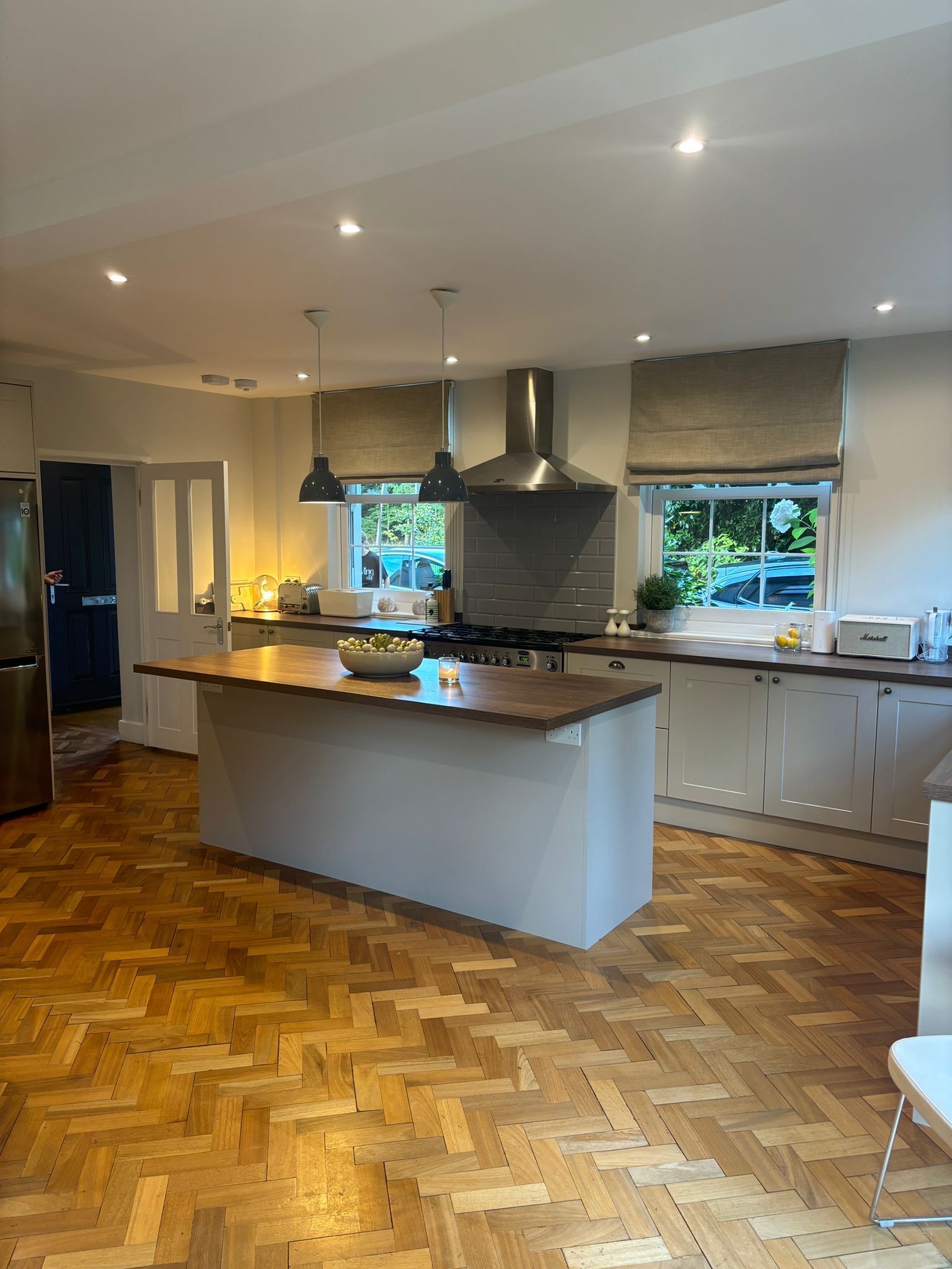 Kitchen with island, wood floor, white cabinets, and stainless steel hood.