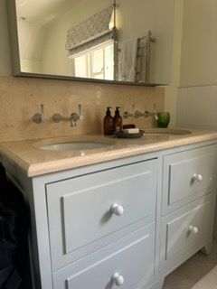 Light blue bathroom vanity with two sinks, cream countertop, and mirror.
