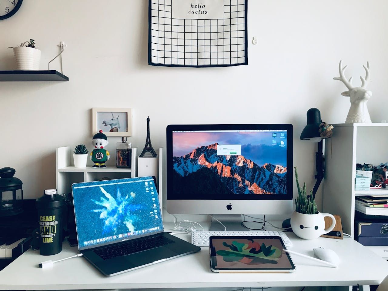 Desk with two computers, an iPad, and various decorative items.