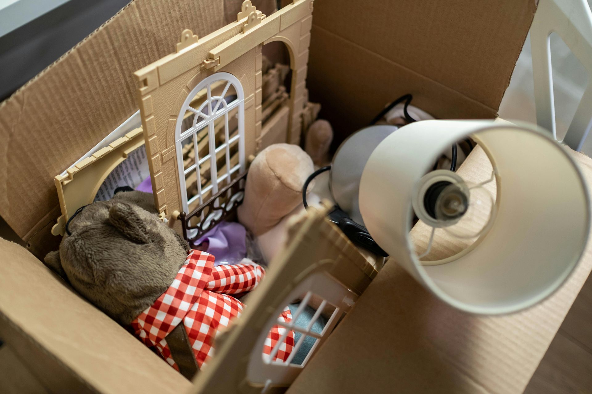 Cardboard box filled with assorted toys and a lampshade.