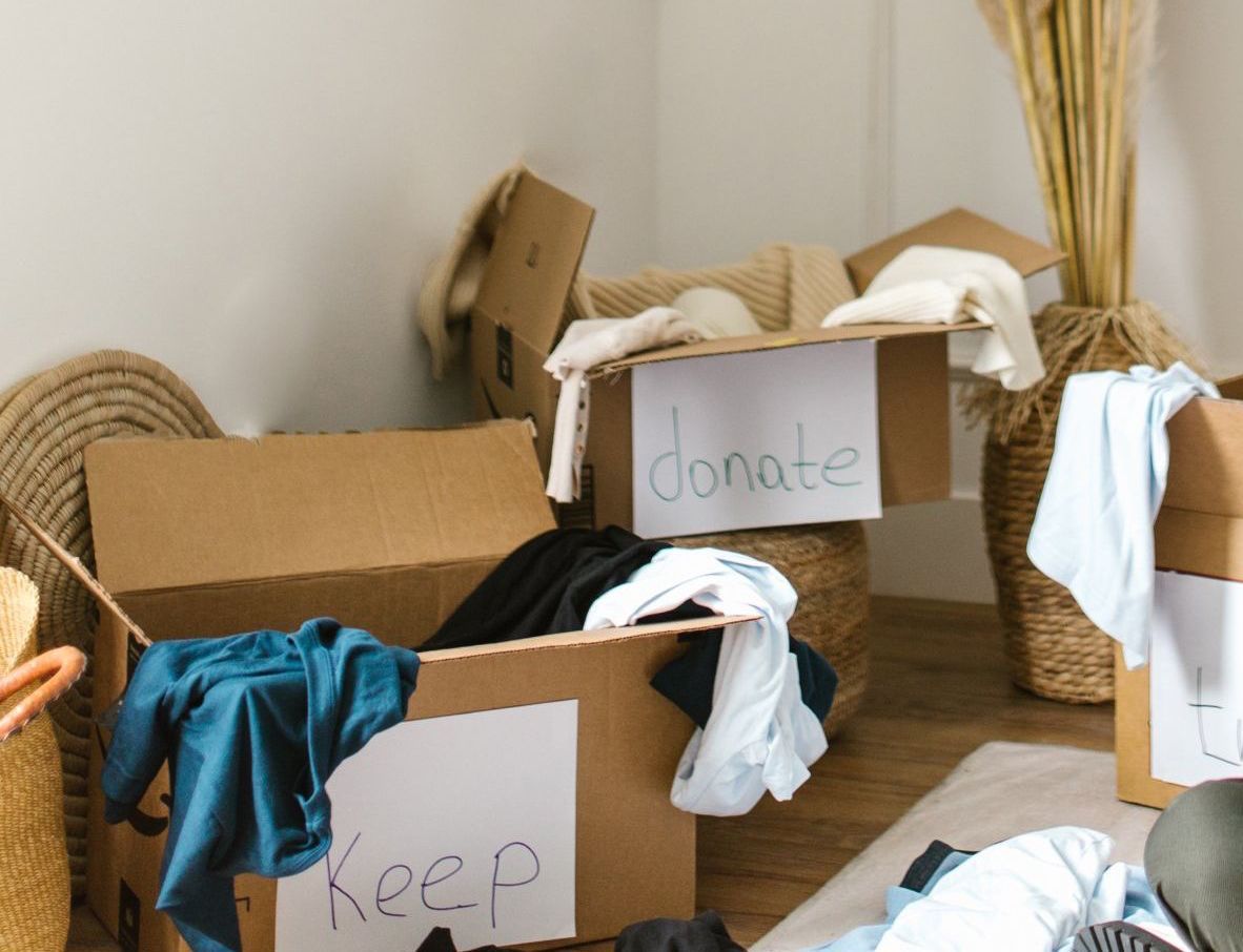 Two cardboard boxes filled with clothes and a sign that says donate and keep.