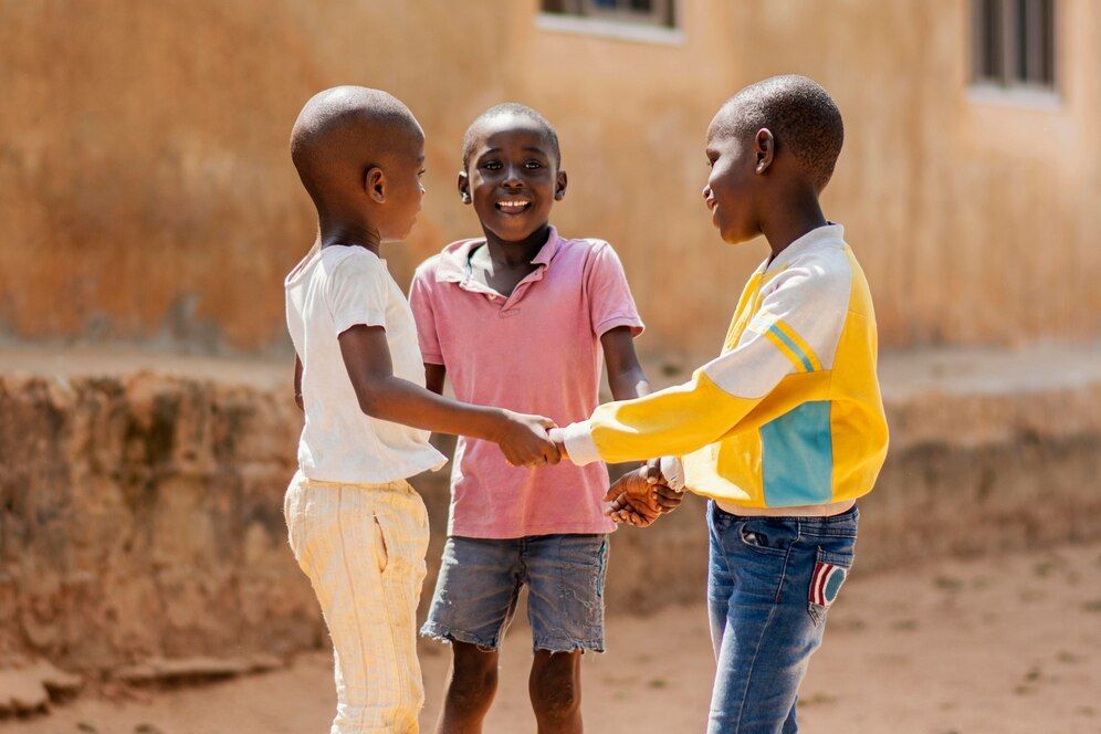 Three children are holding hands and talking to each other.