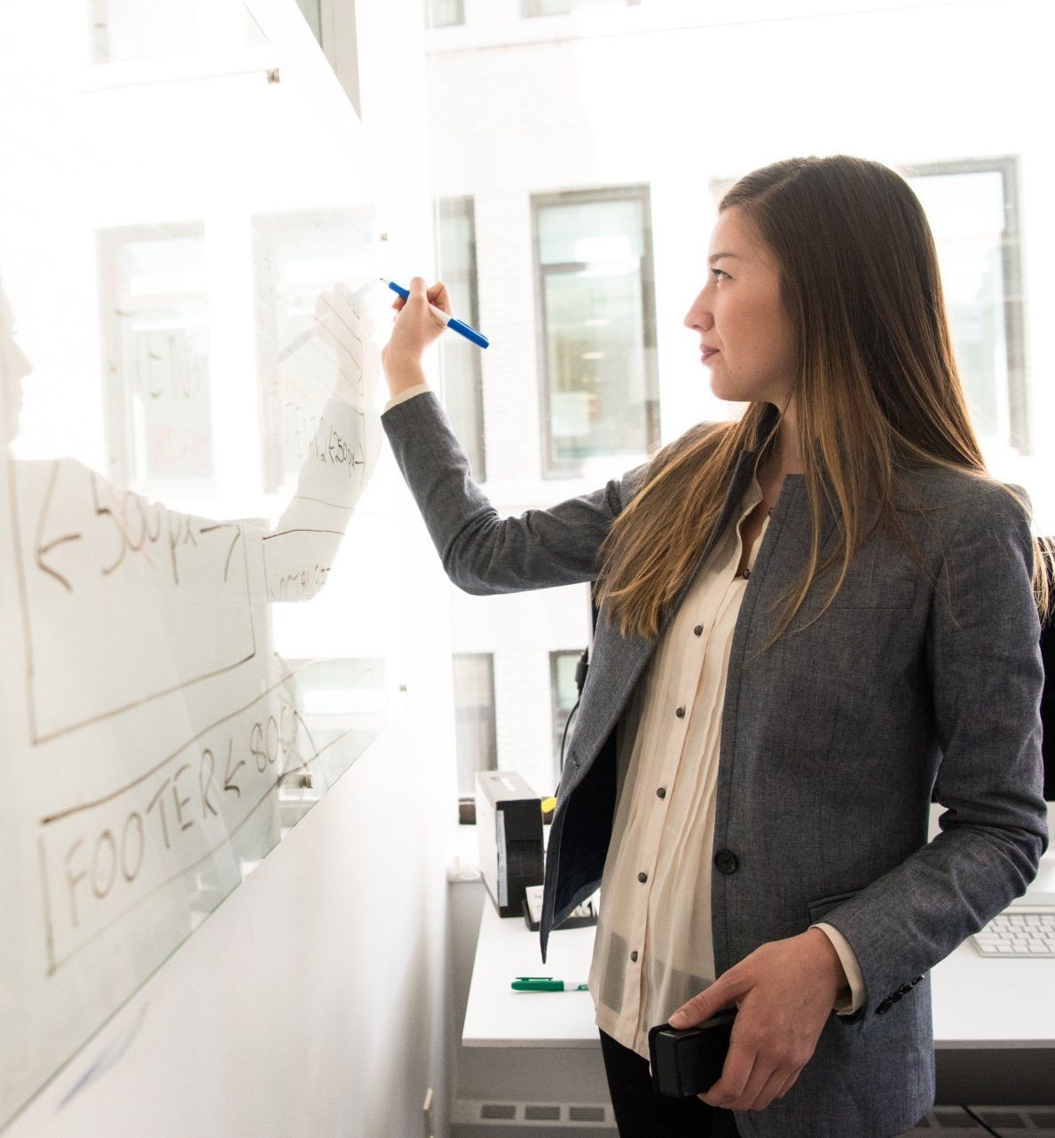 A woman is writing on a white board with a pen