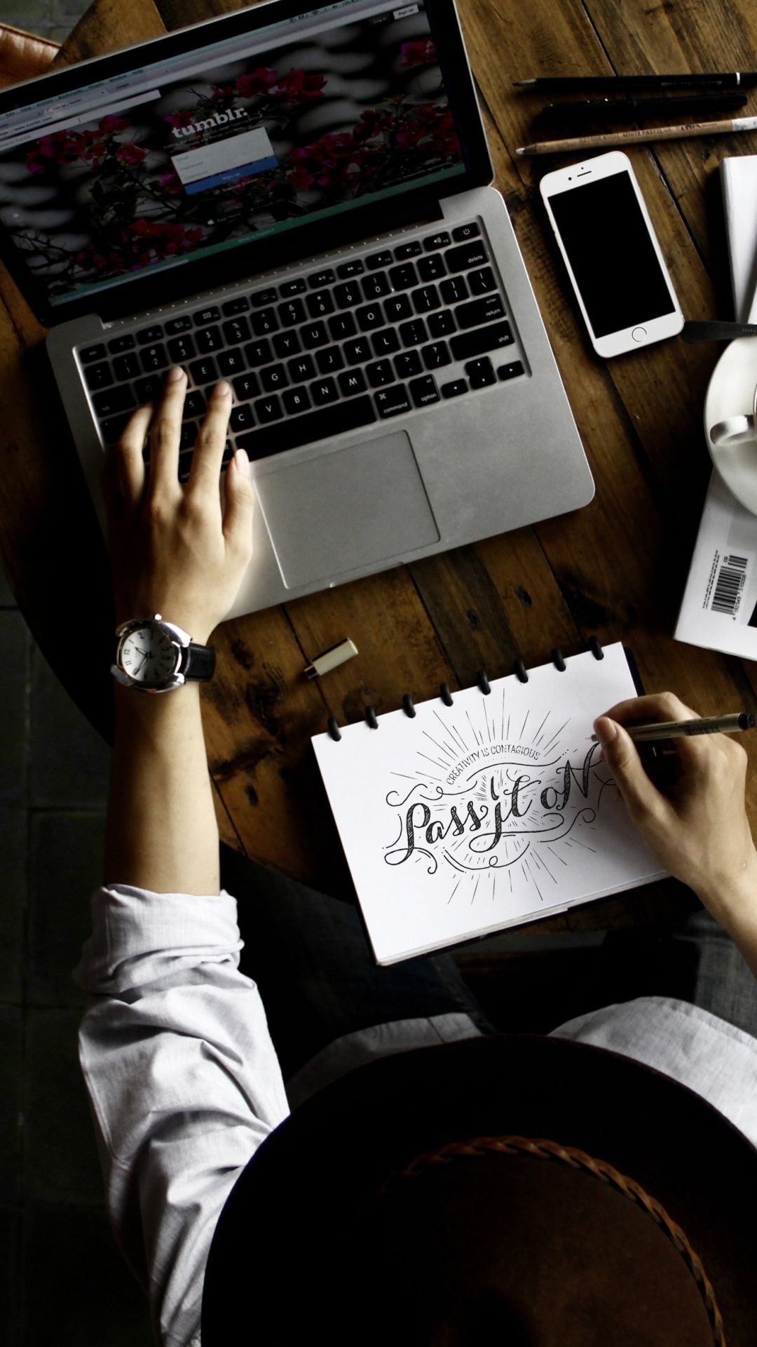 A person is writing on a piece of paper in front of a laptop computer.